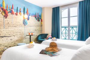 two beds in a room with a beach mural at SOWELL HOTELS Le Beach in Trouville-sur-Mer