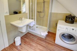 a bathroom with a shower and a sink and a washing machine at fewo1846 - Kajuete am Nordermarkt - maritim eingerichtetes Studio-Apartment im Stadtzentrum in Flensburg