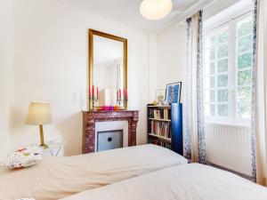 a bedroom with a bed and a mirror and a fireplace at Villa Le Cyclamen by Interhome in Courseulles-sur-Mer