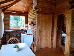 a kitchen in a log cabin with a table and a refrigerator at Cabañas Artemisa in Tandil