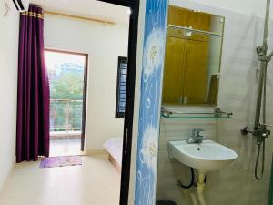 La salle de bains est pourvue d'un lavabo, d'un miroir et d'une fenêtre. dans l'établissement Haiphong Backpacker Hostel, à Hai Phong