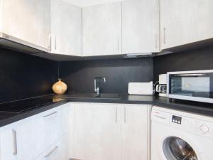 een keuken met witte kasten, een wastafel en een magnetron bij Apartment Résidence Capao-1 by Interhome in Cap d'Agde