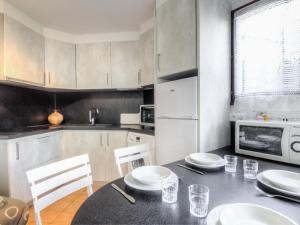 een keuken met een tafel en stoelen en een magnetron bij Apartment Résidence Capao-1 by Interhome in Cap d'Agde