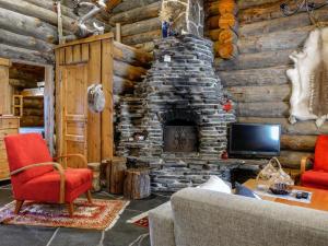 a living room with a stone fireplace in a log cabin at Holiday Home Kelo-ville by Interhome in Luosto