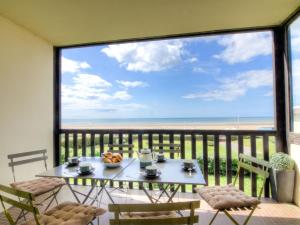 a table and chairs on a balcony with a view of the beach at Apartment Neptune by Interhome in Bénerville-sur-Mer