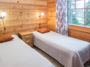 two beds in a room with wooden walls at Holiday Home Vuosselin trio a by Interhome in Ruka