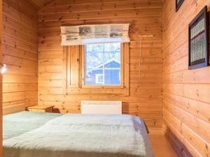 1 dormitorio en una cabaña de madera con cama y ventana en Holiday Home Lomaylläs h109 -pistopolku 1 a by Interhome en Ylläsjärvi
