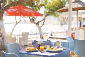 einem blauen Tisch mit Teller mit Lebensmitteln und einem roten Regenschirm in der Unterkunft MINOS BEACH KARPATHoS in Karpathos