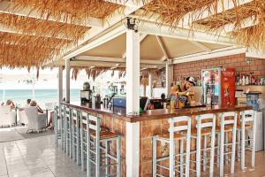 un restaurante con un bar con sillas en la playa en MINOS BEACH KARPATHoS en Kárpatos