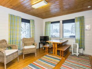 ein Wohnzimmer mit einem Tisch, Stühlen und Fenstern in der Unterkunft Holiday Home Piilopirtti by Interhome in Juhanala