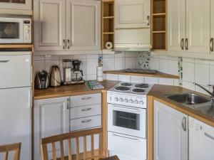 eine Küche mit weißen Geräten und Holzschränken in der Unterkunft Holiday Home Alppinuppu by Interhome in Tahkovuori