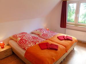- une chambre avec un lit doté de draps et d'oreillers orange dans l'établissement Apartment Landblick-2 by Interhome, à Süderneuland Zwei
