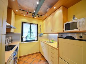 eine gelbe Küche mit einer Spüle und einer Mikrowelle in der Unterkunft Holiday Home Kapitänshaus by Interhome in Groß Zicker