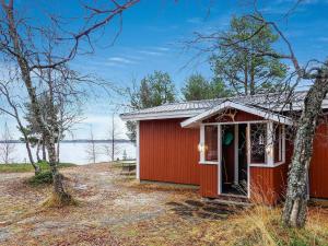 a red building with a porch in the woods at Holiday Home Mellaniemi by Interhome in Hietajoensuu
