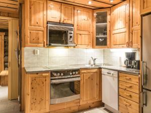 eine Küche mit Holzschränken und einem Herd mit Backofen in der Unterkunft Holiday Home Operonmukka a 8 by Interhome in Levi