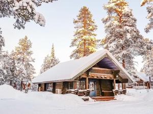 drewniany domek na śniegu z drzewami w obiekcie Holiday Home Tikkatupa by Interhome w mieście Levi