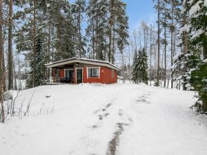 a small red cabin in the woods in the snow at Holiday Home Hiekkasaari by Interhome in Juhanala