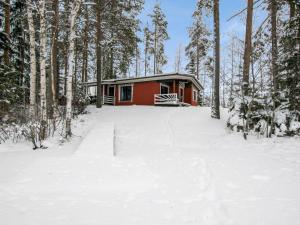 uma cabana vermelha na floresta na neve em Holiday Home Hiekkasaari by Interhome em Juhanala