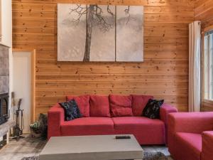 ein Wohnzimmer mit einem roten Sofa und Holzwänden in der Unterkunft Holiday Home Aurinko-saga by Interhome in Ylläsjärvi