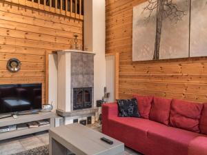 ein Wohnzimmer mit einem roten Sofa und einem Kamin in der Unterkunft Holiday Home Aurinko-saga by Interhome in Ylläsjärvi