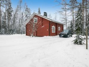 Juhanala的住宿－瓦特拉卡維洛瑪克斯庫度假屋，雪上的一个红色谷仓,旁边停着一辆汽车