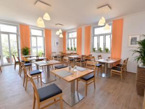 un restaurante con mesas y sillas de madera y ventanas en Pension Gambrinus en Passau