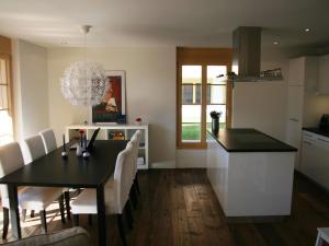 uma cozinha e sala de jantar com uma mesa preta e cadeiras brancas em Apartment Mühleport 1 by Interhome em Adelboden