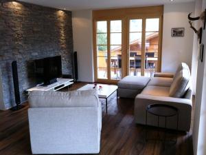 a living room with two couches and a tv at Apartment Mühleport 1 by Interhome in Adelboden