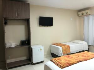 a hotel room with two beds and a flat screen tv at Pousada El Shaddai in Foz do Iguaçu