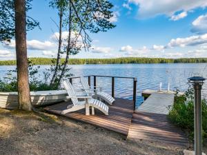 un muelle con 2 sillas y un barco en un lago en Holiday Home Kuvalanranta by Interhome en Mouhu