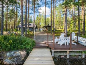 un puente de madera con 2 bancos y un cenador en Holiday Home Kuvalanranta by Interhome en Mouhu