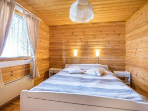 ein Schlafzimmer mit einem Bett in einem Holzzimmer in der Unterkunft Holiday Home Mäntykumpu by Interhome in Petäjävesi
