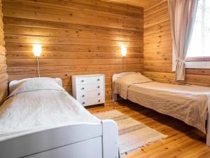 two beds in a room with wooden walls at Holiday Home Mäntykumpu by Interhome in Petäjävesi
