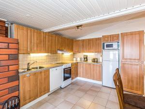 a kitchen with wooden cabinets and white appliances at Holiday Home Beach 2 - 5664 by Interhome in Vääksy