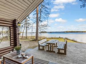 a porch with two benches and a table and a lake at Holiday Home Beach 2 - 5664 by Interhome in Vääksy