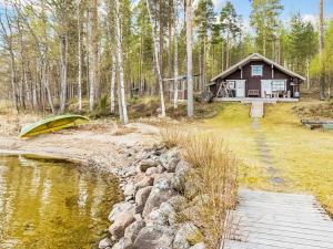 a log cabin with a boat in front of a pond at Holiday Home Beach 2 - 5664 by Interhome in Vääksy