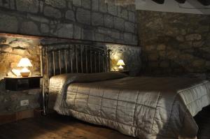 a bedroom with a bed with stone walls and two lamps at Case Eleutheria in Petralia Soprana