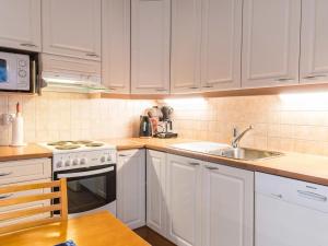 een keuken met witte kasten, een wastafel en een fornuis bij Holiday Home Aamutähti by Interhome in Äkäslompolo