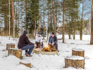 três pessoas sentadas à volta de uma fogueira na neve em Holiday Home Päätalo by Interhome em Vääksy