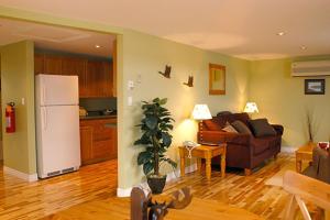ein Wohnzimmer mit einem Sofa und einem Kühlschrank in der Unterkunft Auberge Bay Wind Suites in Chéticamp