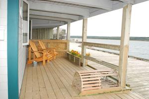 a deck with two chairs and a table on a dock at Auberge Bay Wind Suites in Chéticamp