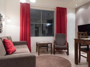 a living room with a couch and a window with red curtains at Holiday Home Yllästar 3 as 502 by Interhome in Äkäslompolo