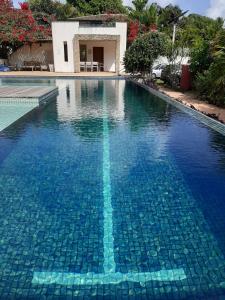 una piscina de agua azul frente a una casa en Apartamentos no Pipa Residence, en Pipa