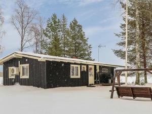 a black building with a bench in the snow at Holiday Home Inninniemi by Interhome in Pyhäsalmi