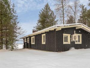 a small black building in the snow with trees at Holiday Home Inninniemi by Interhome in Pyhäsalmi