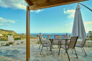 une terrasse avec une table, des chaises et un parasol dans l'établissement Maria's cozy stonehouse, à Kerames