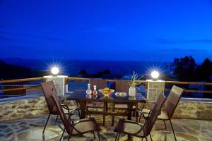 einen Tisch und Stühle auf einer Terrasse in der Nacht in der Unterkunft Maria's cozy stonehouse in Kerames