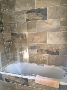 uma banheira na casa de banho com uma parede de azulejos em The Kings Head em Louth