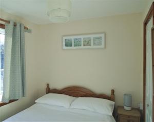 a bedroom with a bed with white sheets and a window at Detached Bungalow in North Cornwall in Bodmin +40 photos