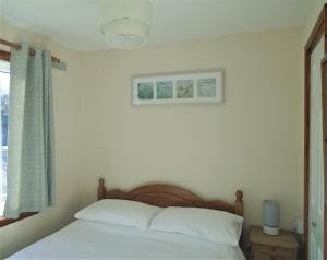 a bedroom with a bed with white sheets and a window at Detached Bungalow in North Cornwall in Bodmin